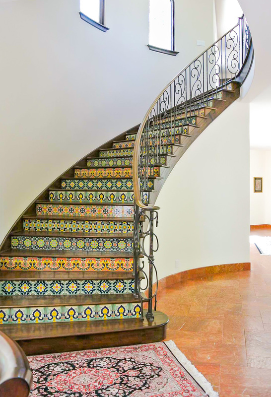Mediterranean style tiled staircase with wrought iron hand rails separates the first and second floors of the Saratoga home designed by Golden Visions Design 